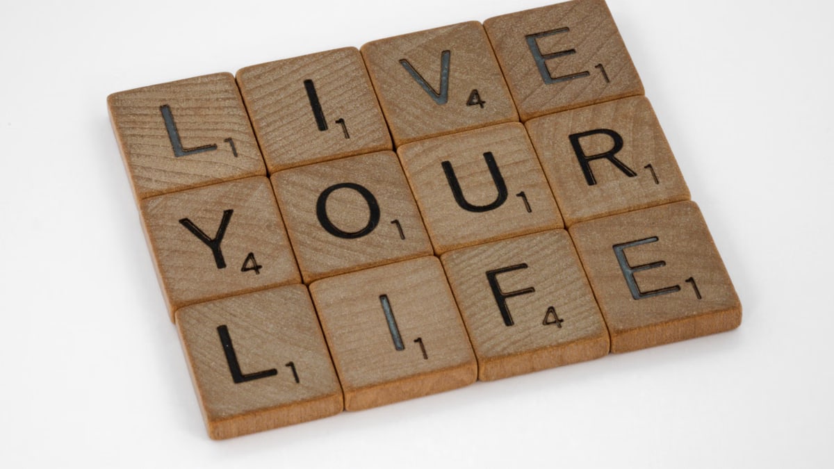 Scrabble tiles form the phrase 'Live Your Life' on a white background.